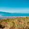 Panoramic view from Mount Vesuvius showing Naples, the Gulf of Naples, and distant Capri island, with Mediterranean vegetation in foreground