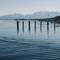 Seven wooden posts standing in calm lake water with snow-capped Bavarian Alps in background at Chiemsee, Germany
