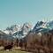 Snow-covered Wilder Kaiser mountain peaks rising dramatically above valley floor with traditional wooden hut and bare trees in Kaisertal, Austria