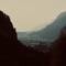 View from Kaisertal valley toward Kufstein town nestled between mountain ridges, with forested slopes framing the atmospheric scene, Austria