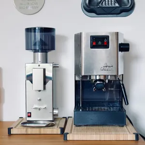 Stainless steel Gaggia Classic espresso machine and matching coffee grinder sitting on wooden platforms on kitchen counter