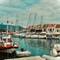 Harbor view of Fiskardo, Greece showing various boats moored in turquoise water with traditional white buildings and red tile roofs along waterfront