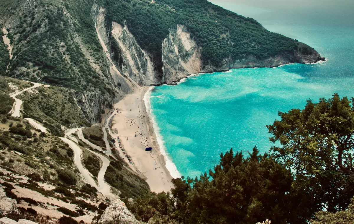 Aerial view of Myrtos Beach in Kefalonia, Greece showing dramatic white cliffs, turquoise waters, and winding access road