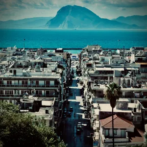 Aerial view of Patras, Greece showing white buildings, main street leading to harbor, mountains across Ionian Sea in background