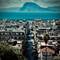 Aerial view of Patras, Greece showing white buildings, main street leading to harbor, mountains across Ionian Sea in background
