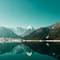 Pristine alpine lake reflecting snow-covered mountains and forested slopes under clear turquoise sky in Achensee, Austria