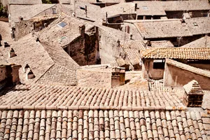 Aerial view of clustered terracotta tile rooftops and stone buildings in Bolsena, Italy, showing traditional Mediterranean architecture