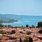 Panoramic view of Bolsena, Italy with terracotta-roofed buildings in foreground overlooking Lake Bolsena and forested hills