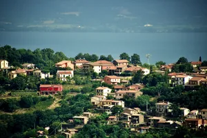 Hillside Italian village with colorful houses and terracotta roofs scattered across terraced slopes, trees interspersed throughout