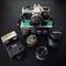 Vintage Olympus OM-10 camera with chrome body, various lenses, flash unit, and lens box arranged on dark surface in Austria