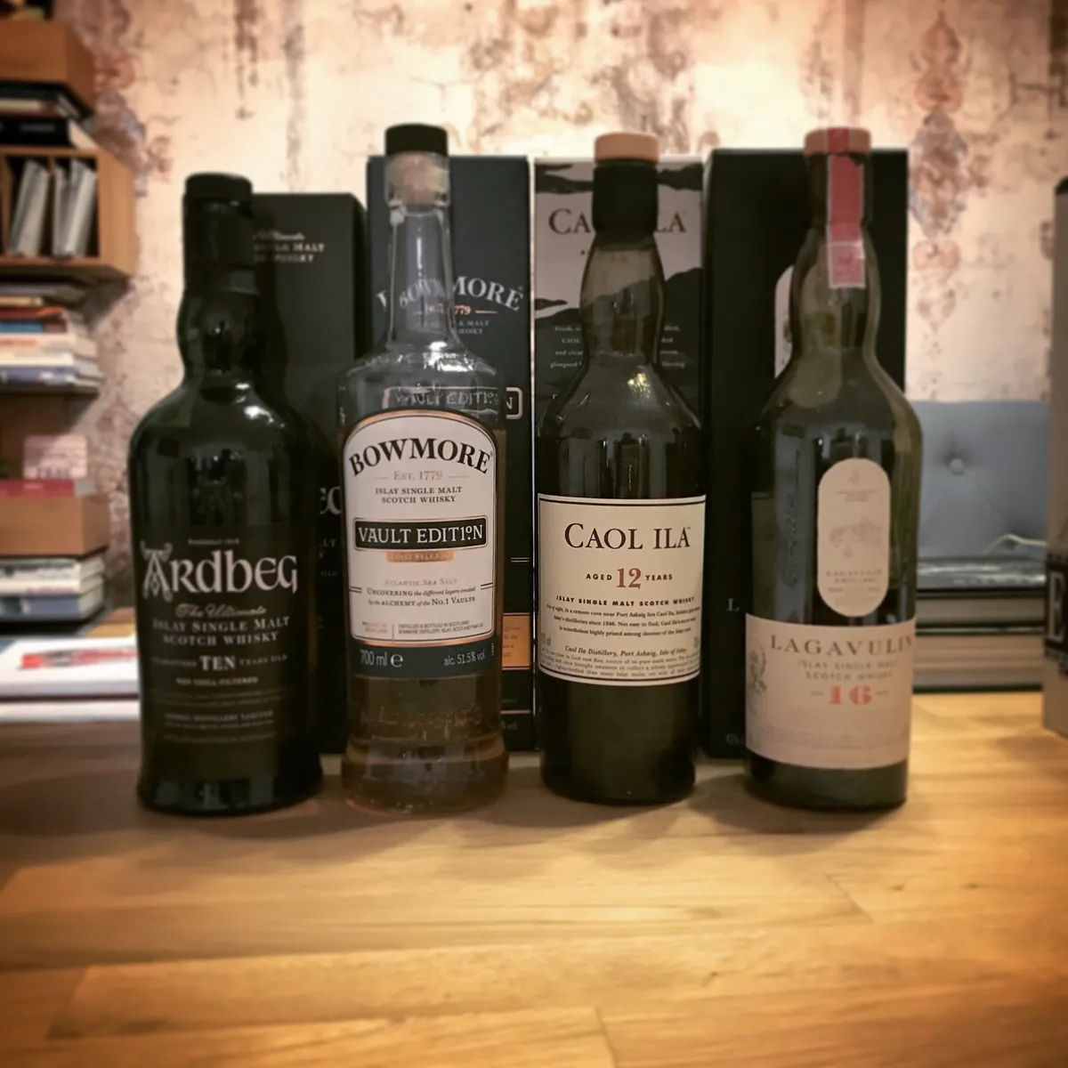 Four bottles of Islay single malt Scotch whisky arranged on wooden surface - Ardbeg, Bowmore, Caol Ila, and Lagavulin brands in Erlau, Austria
