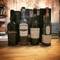 Four bottles of Islay single malt Scotch whisky arranged on wooden surface - Ardbeg, Bowmore, Caol Ila, and Lagavulin brands in Erlau, Austria