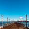 Long wooden pier extending over San Francisco Bay with ornate lampposts, metal railings, and people walking, Telegraph Hill, California