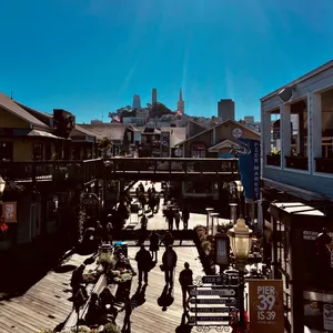 Multi-level wooden pier marketplace with shops, restaurants, directional signs, and tourists walking around at Pier 39, Fisherman's Wharf, California