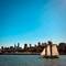 Two-masted sailing schooner with cream sails on San Francisco Bay with downtown city skyline and blue sky in background