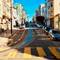 Steep San Francisco street with cable car tracks running uphill between colorful Victorian buildings, yellow crosswalk stripes in foreground