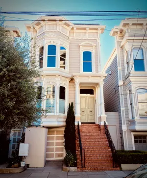 Victorian house with ornate white trim, bay windows, and brick front steps - the Full House exterior filming location in San Francisco