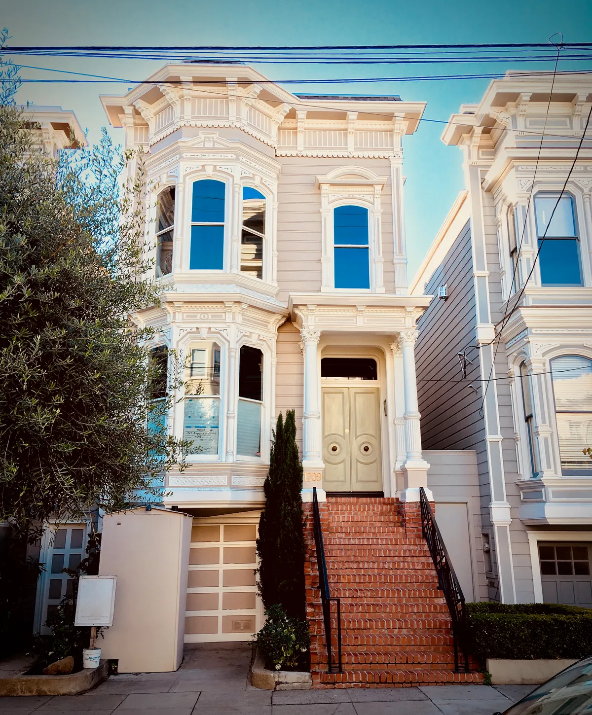 Victorian house with ornate white trim, bay windows, and brick front steps - the Full House exterior filming location in San Francisco