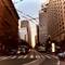 Downtown San Francisco street view with cable car overhead wires, tall buildings on both sides, buses and traffic during evening rush hour