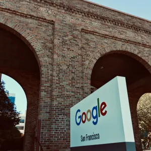 Google San Francisco office sign on white wall beneath large brick archways of converted industrial warehouse building
