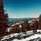 Skiers gathered on snowy mountain slope overlooking Lake Tahoe with snow-covered pine forests and distant mountains in El Dorado County
