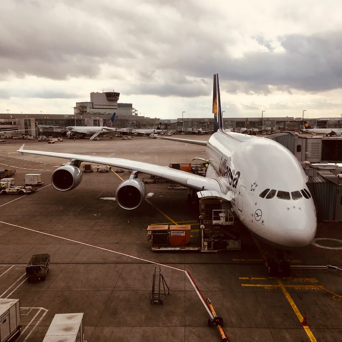 Lufthansa Airbus A380 aircraft parked at gate with ground equipment and terminal buildings at Frankfurt Airport, Germany