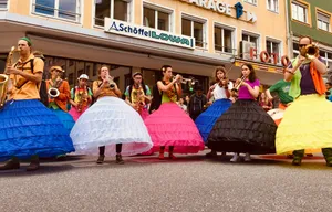 Street musicians in large colorful puffy skirts playing brass instruments during outdoor performance in Innsbruck, Austria