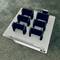 Six black 3D printed battery holders arranged on white build plate sitting on textured asphalt surface in Erlau, Austria